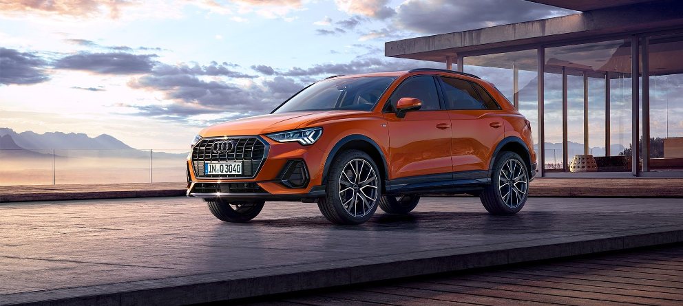 Audi Q3 naranja aparcado ante una puesta de sol. | eligetucoche.es